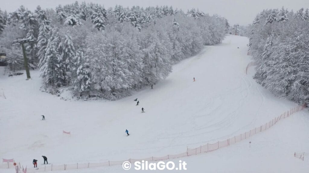 Pista da sci a Camigliatello Silano con sciatori in azione.